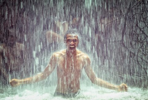 Mann kühlt sich unter Wasserfall ab