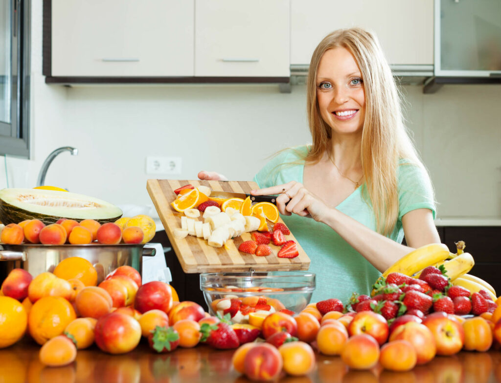 Frau schneidet Früchte für Obstsalat